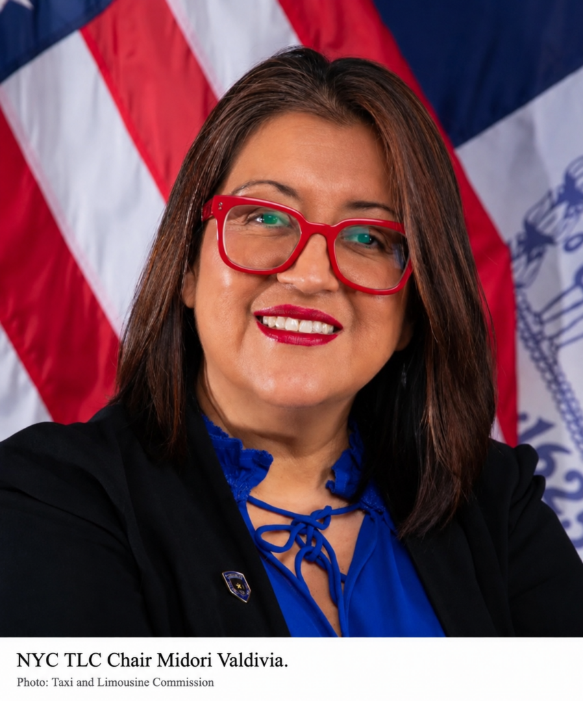 NYC TLC Chair Midori Valdivia wearing red glasses in front of an American flag